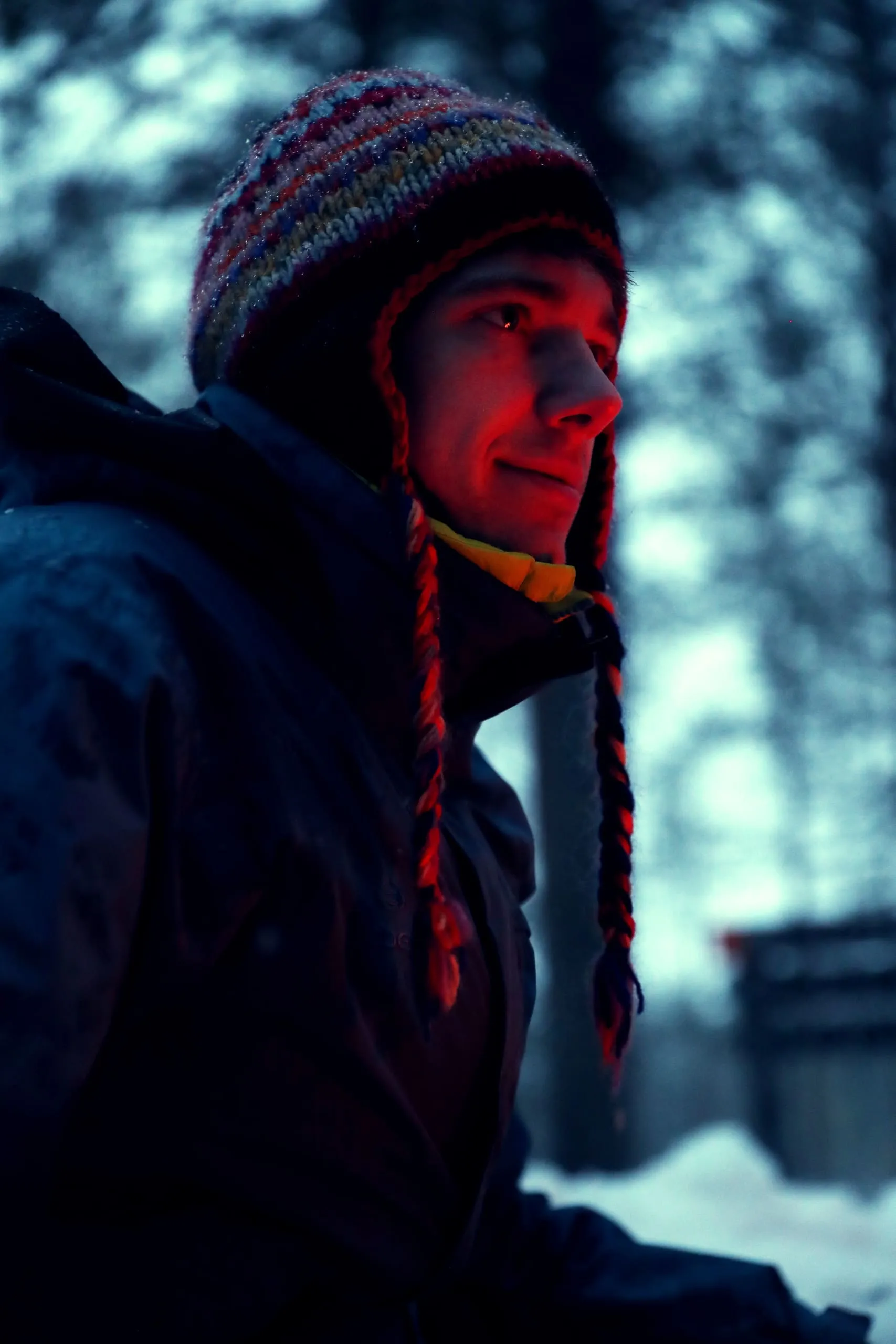 Portret van iemand met een gebreide muts met vlechten, van opzij gezien, in warm licht.
